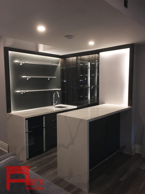 Modern Wet Bar With Austrian Laminate, Quartz Waterfall Countertop, And Floating Glass Display