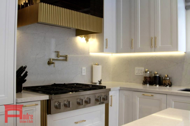 Transitional Kitchen With Painted Mdf And Piano Finish High Gloss Exterior, Quartz Countertop And Backsplash, Waterfall Island, And Custom Mantle Hood With Golden Metallic Frame